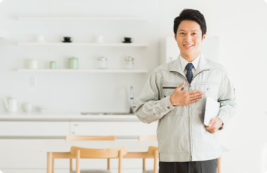 手のひらを胸に当て安心感を与える作業着を着た男性スタッフ